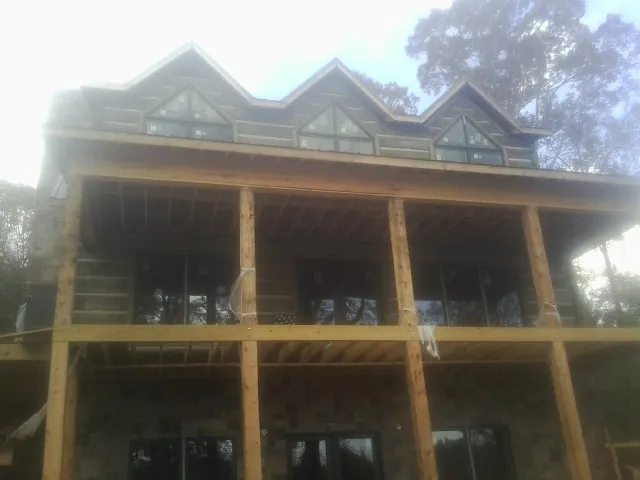 Dormers and porch framing on a large log home under construction — Roof Coating work by our crew in Waverly